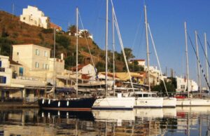 Η Κέα κορυφαίο μυστικό νησί για πεζοπορία και καταδύσεις Ιστιοφόρα και σκάφη αγκυροβολημένα στο λιμάνι του Κόρφου στην Κέα, με παραδοσιακά κτίρια στο φόντο.