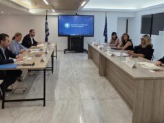 Στελέχη του Υπουργείου Τουρισμού και του ΣΕΤΕ σε συνάντηση εργασίας γύρω από τραπέζι, με την επωνυμία του Υπουργείου Τουρισμού σε οθόνη στο βάθος.