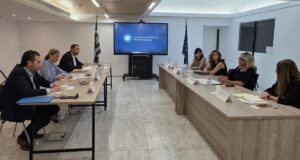 Στελέχη του Υπουργείου Τουρισμού και του ΣΕΤΕ σε συνάντηση εργασίας γύρω από τραπέζι, με την επωνυμία του Υπουργείου Τουρισμού σε οθόνη στο βάθος.