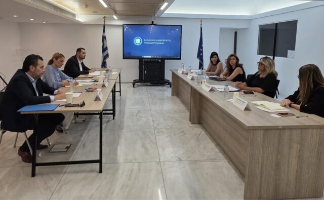 Στελέχη του Υπουργείου Τουρισμού και του ΣΕΤΕ σε συνάντηση εργασίας γύρω από τραπέζι, με την επωνυμία του Υπουργείου Τουρισμού σε οθόνη στο βάθος.